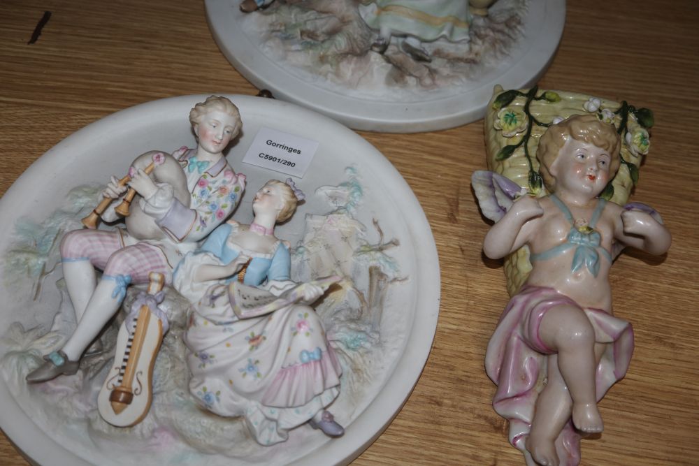 A group of Continental porcelain wall plaques and pockets and a figure group
